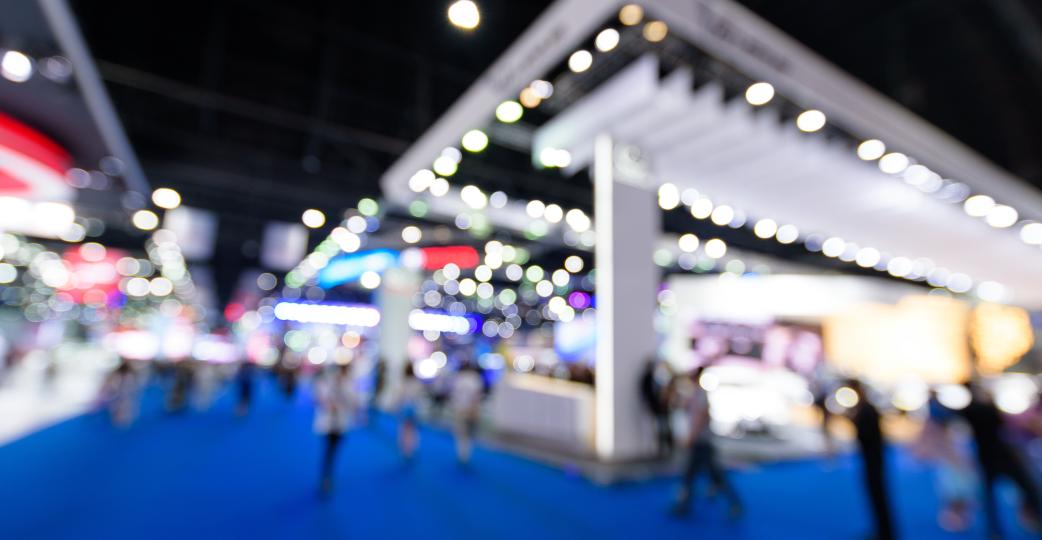 Floor of a trade show showing booth and people with blurred effect