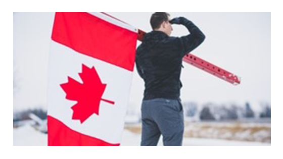 A man holding a Canadian flag looking into the distance