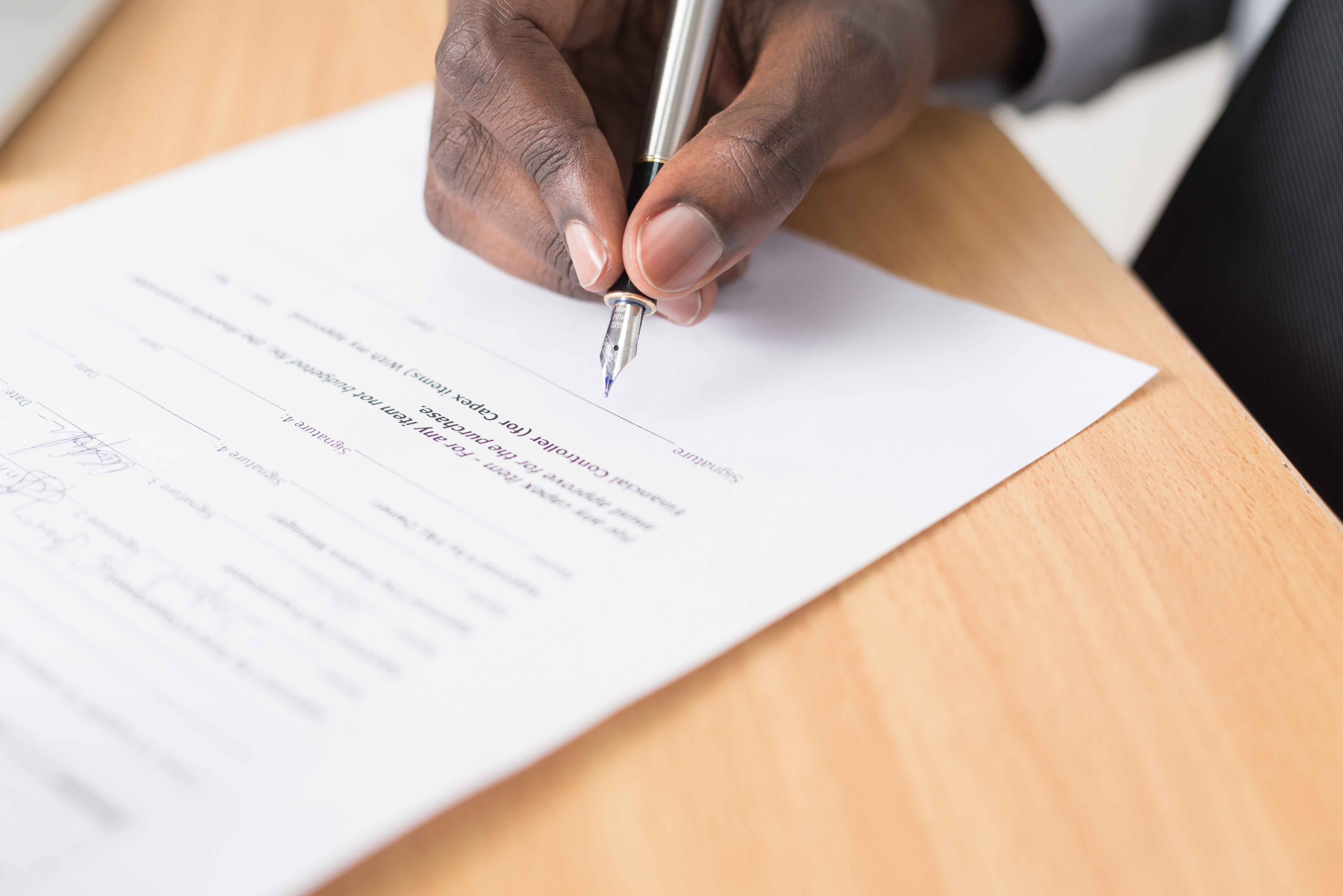 Hand holding a pencil filling out a form on a desk