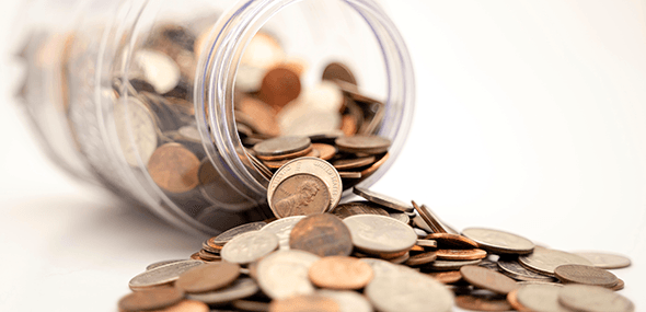 A jar laid on it's side with coins pouring out onto a white surface