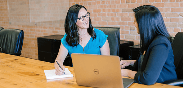 Two women having a professional discussion with at laptop computer in the foreground