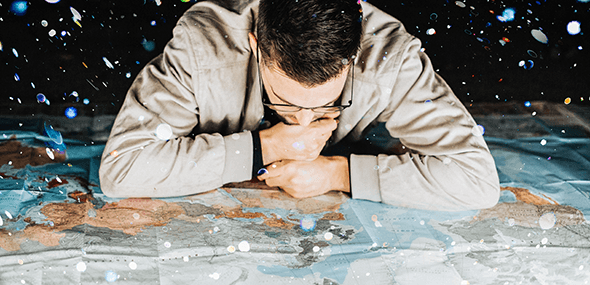 close up of a man studying a map laid out on a floor