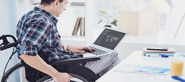 Man sitting in wheelchair studies his laptop.