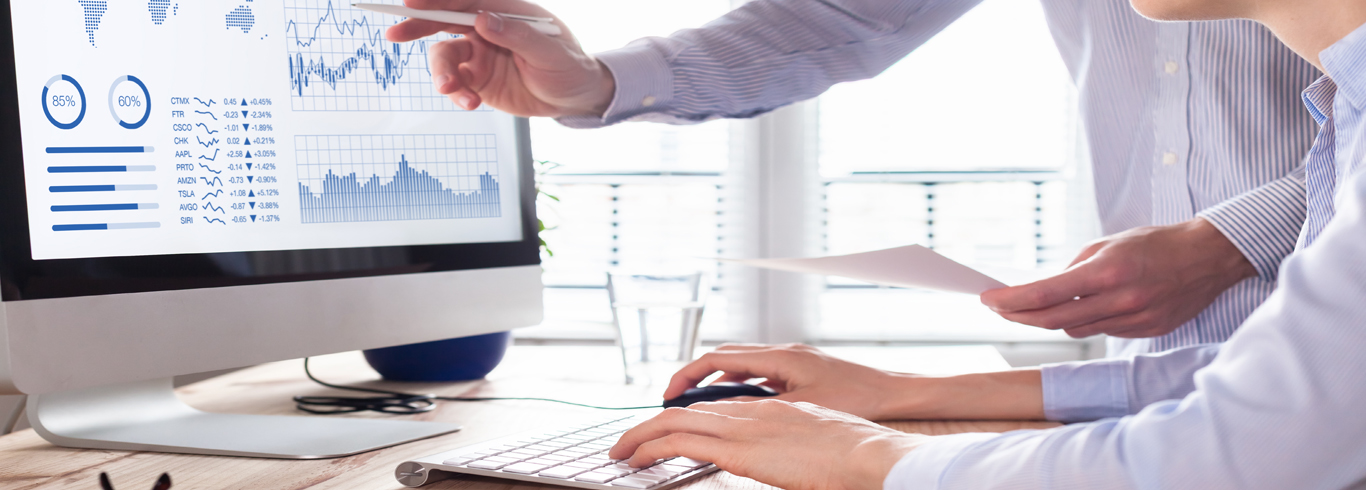 Two people looking at materials on a desktop computer. 