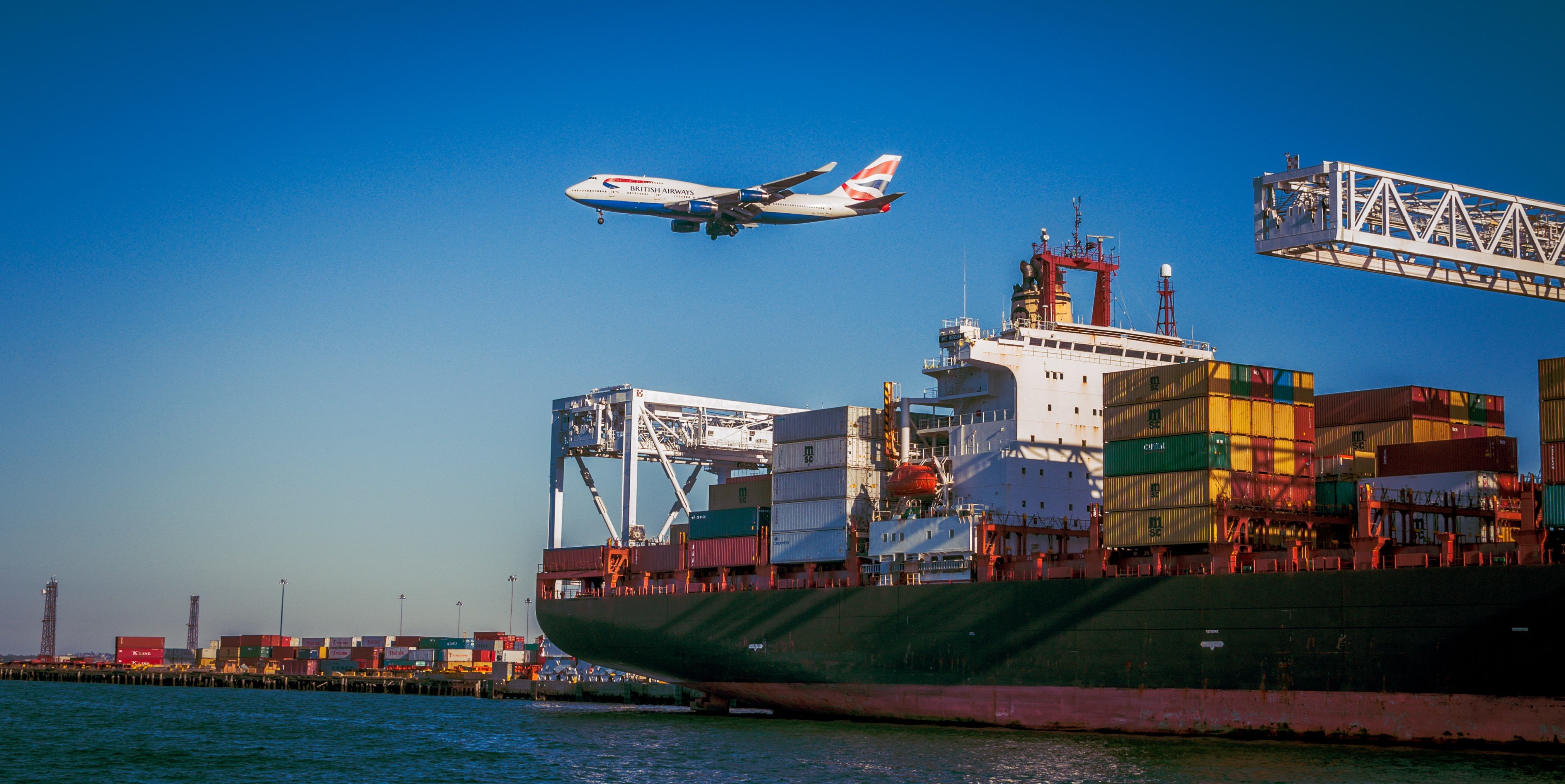 Large shipping ship with a plane flying in the background