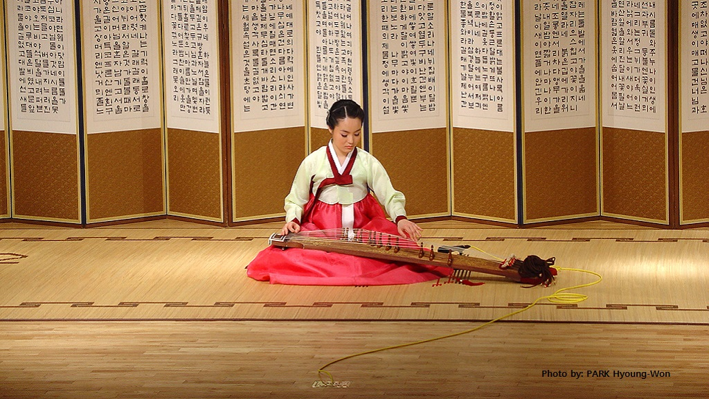 A musician playing a 12-string sanjo gayageum.  