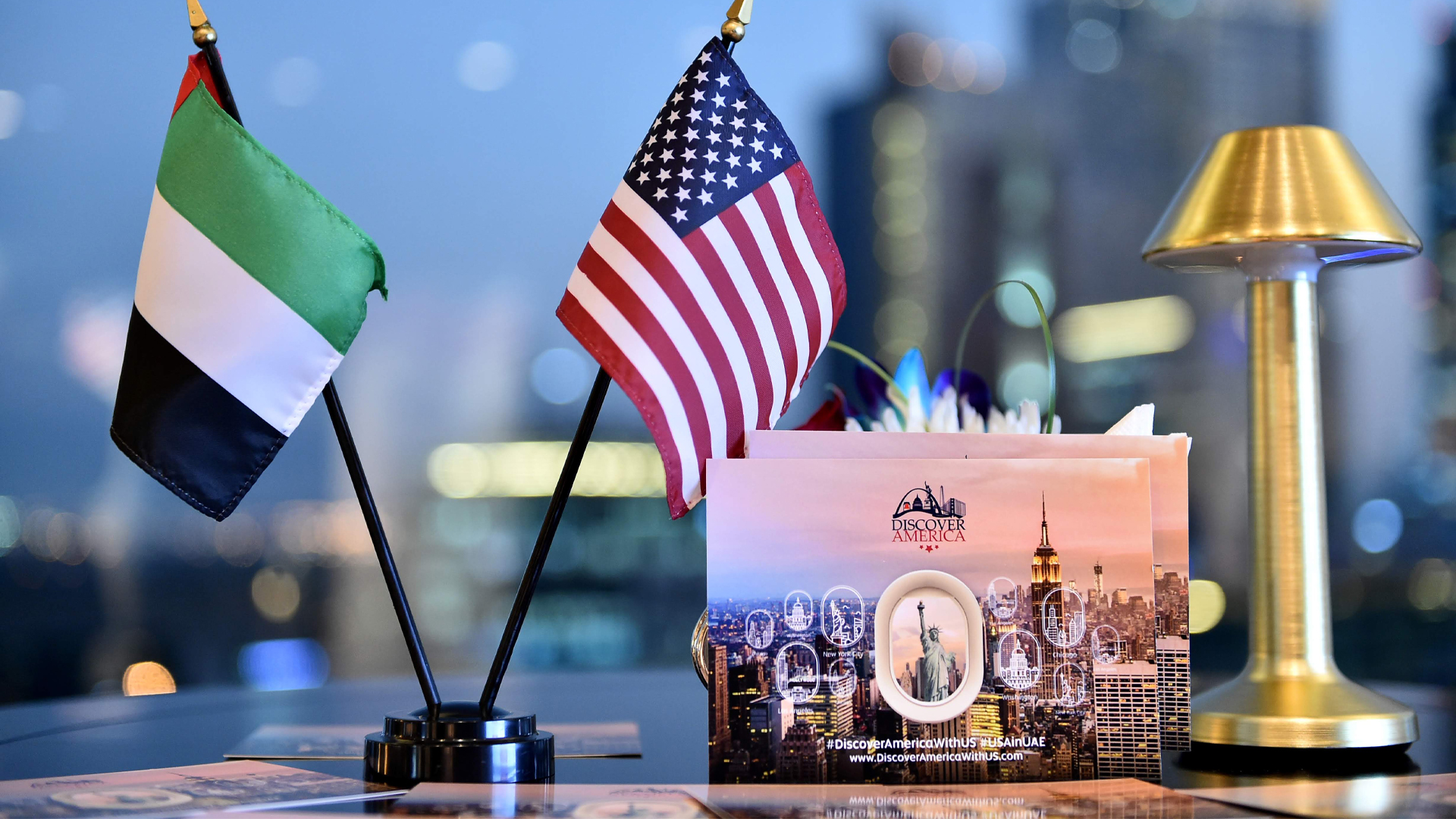 American and UAE Flags on a table with a Discover America Postcard