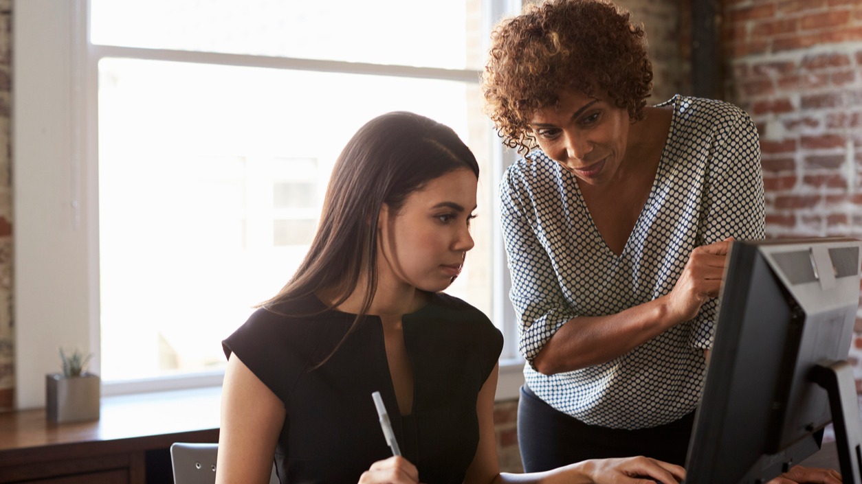 Two Businesswomen Working On Computer In Office.