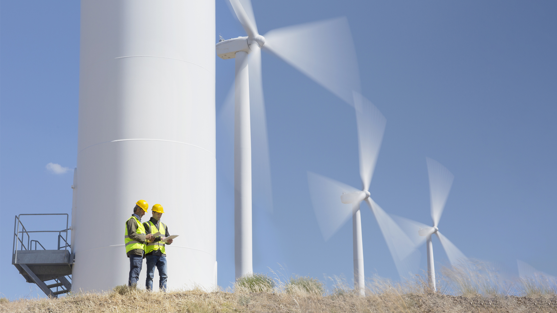Workers Talking By Wind Turbines in Rural Landscape Image for Hero Box