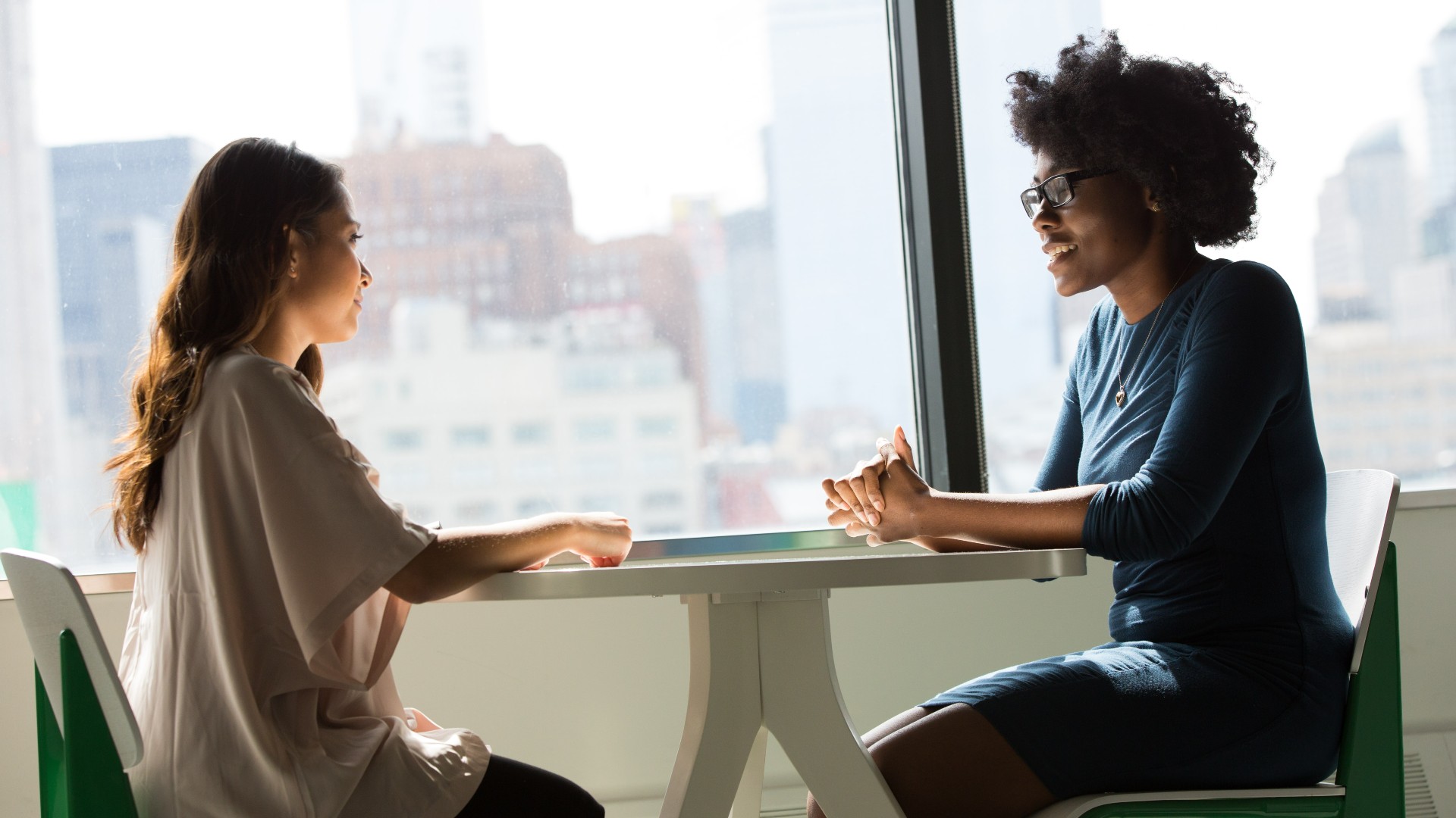 two woman sitting talking in table