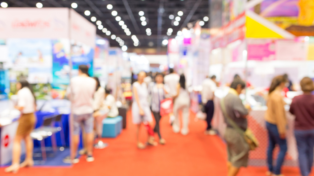 Blurred image of people walking around an exhibition hall at an event.