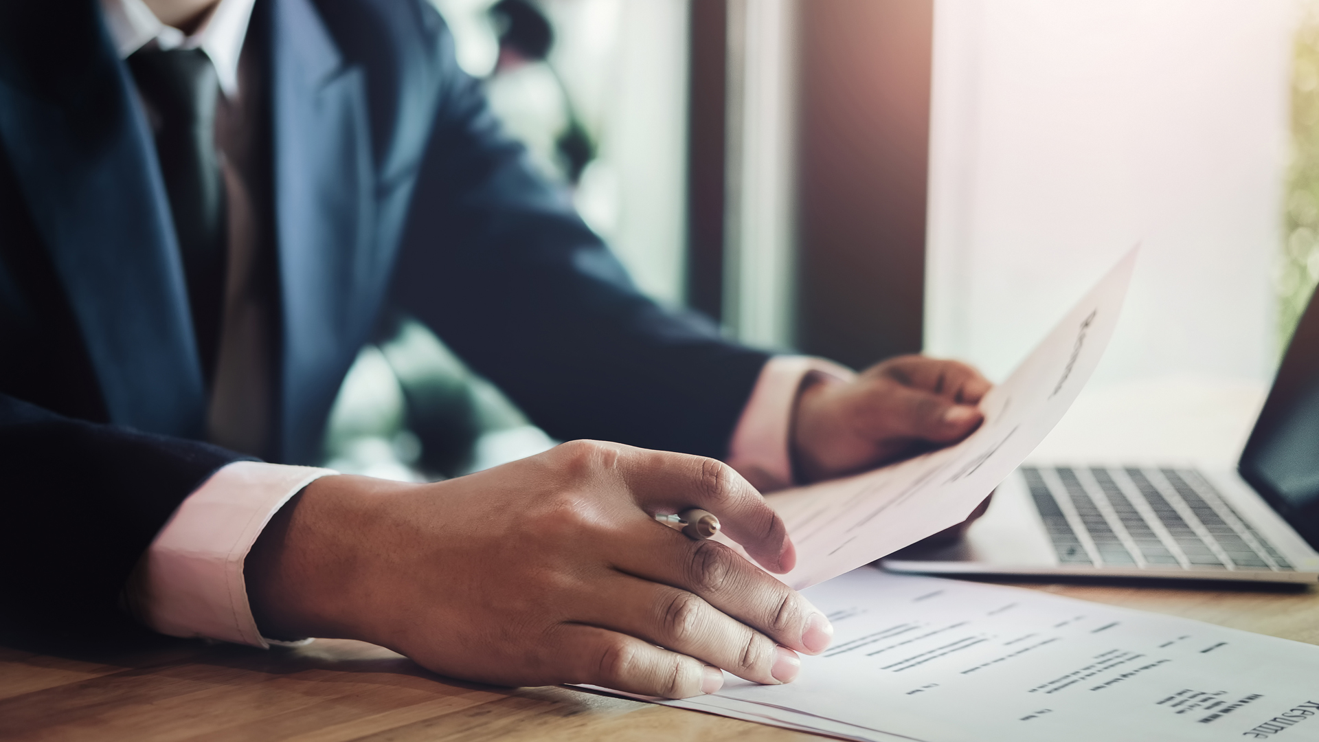 Business man reading agreement paper before sign document with use pen and laptop at work during the day time