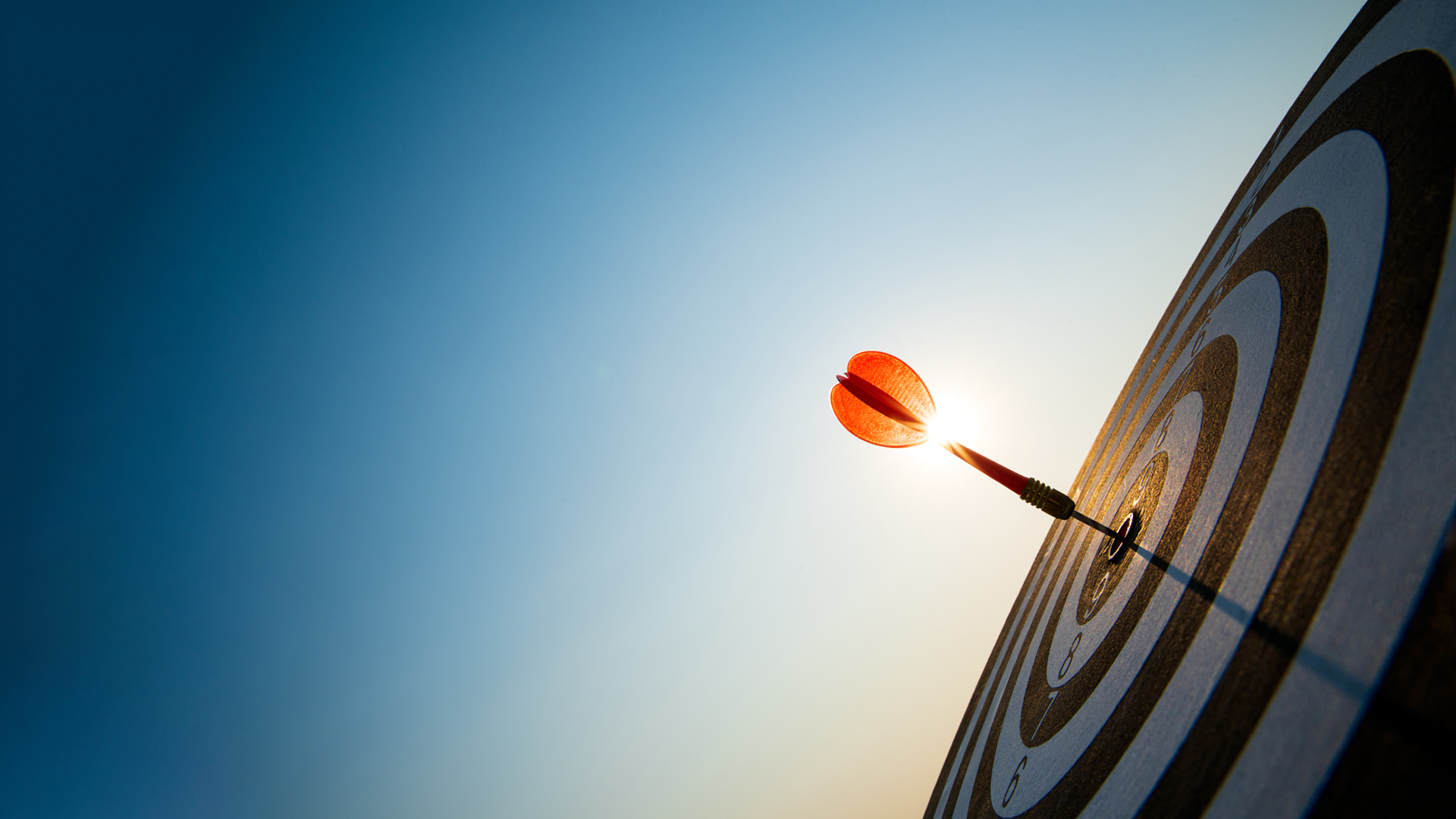 Close up shot red darts arrows in the target center on dark blue sky background. Business target or goal success and winner concept Image