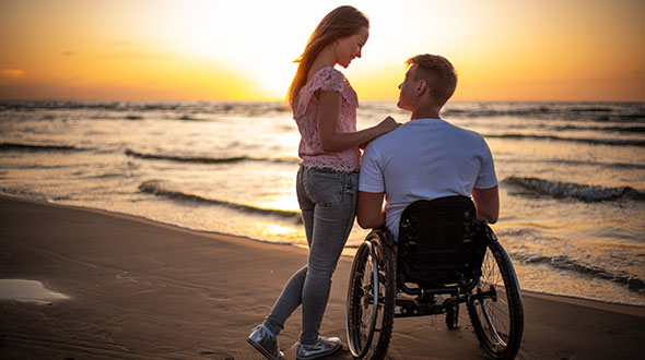 couple on the beach at sunset, man in wheelchair