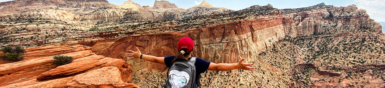 lady standing with outstretched arms, at top of mountain