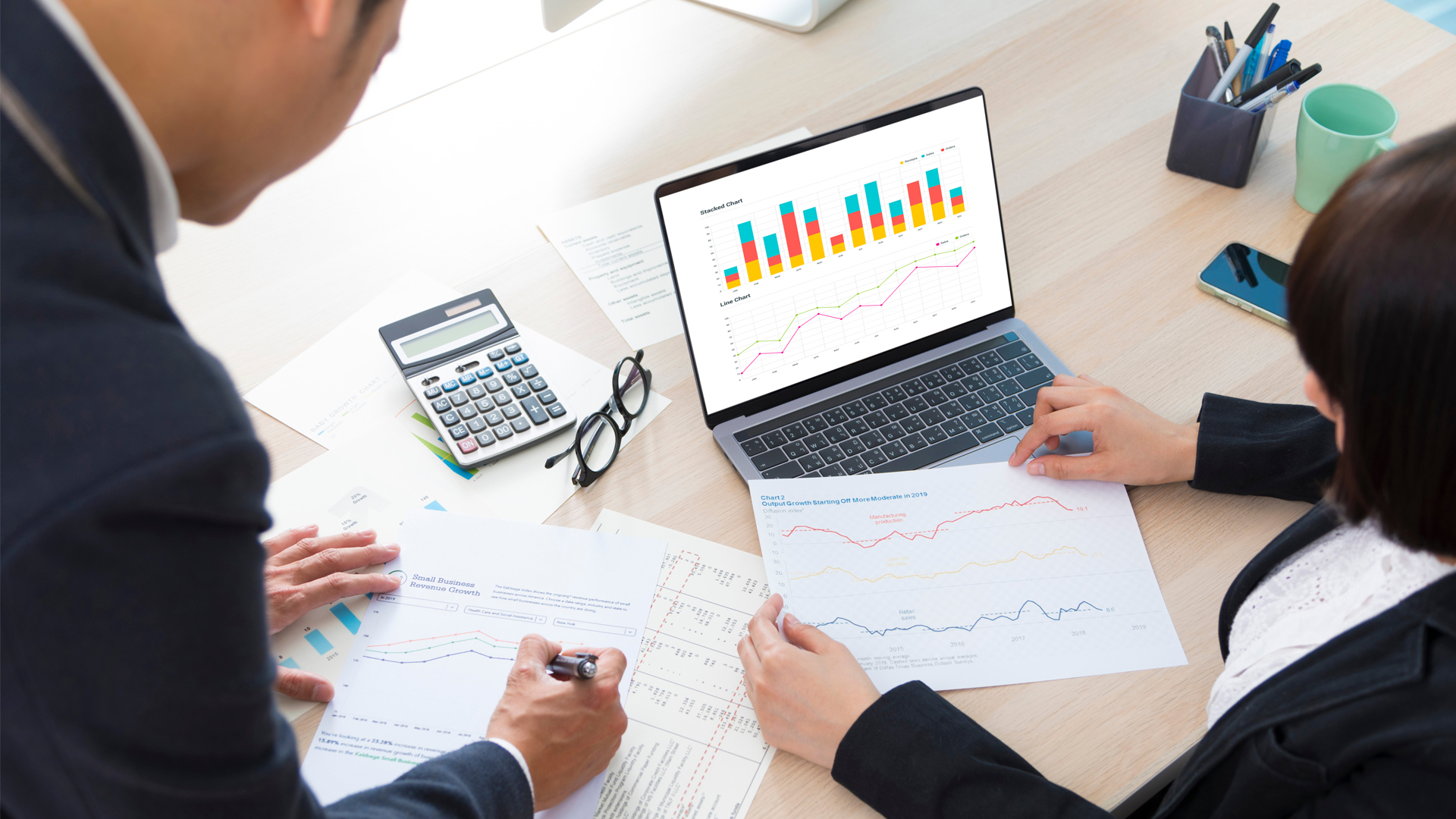 Business man and business woman looking at graphs on a table