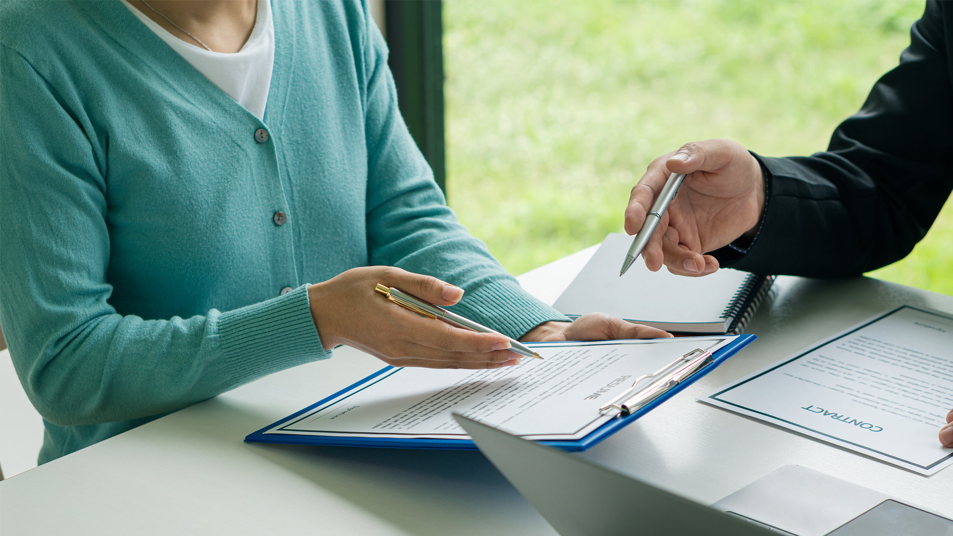 Man explaining what is talked about in a document to a woman in a office during the day