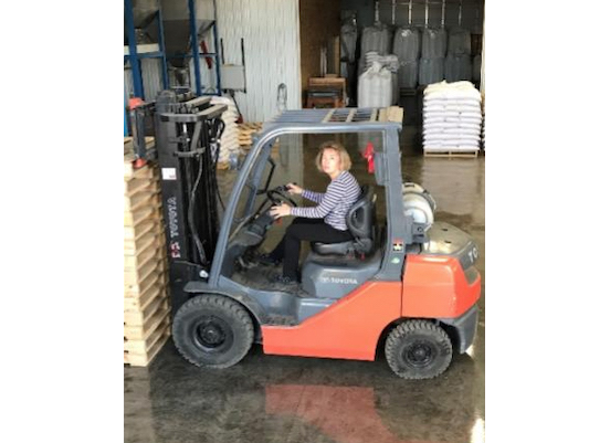 Woman operating a black folk lift in a warehouse