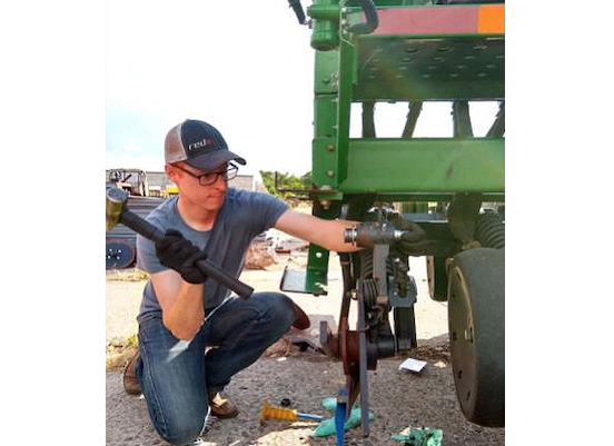 A man working on a piece of farming equipment