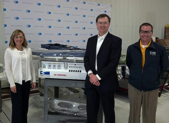 Two men and one woman standing next to a Spectrum Aeromed machine