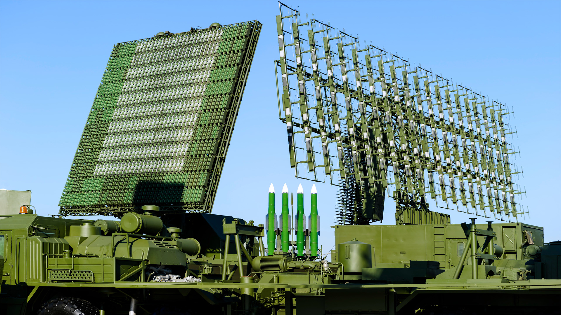 Air defense radars of military mobile antiaircraft systems in green color and ballistic rocket launcher with four cruise missiles in centre of frame, modern army industry image.