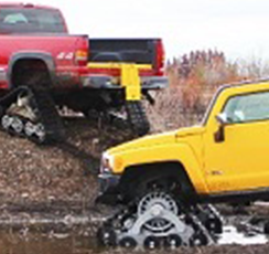 Two trucks using mttracks to get up muddy road