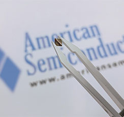 Chip held over the American Semiconductor logo that is blue