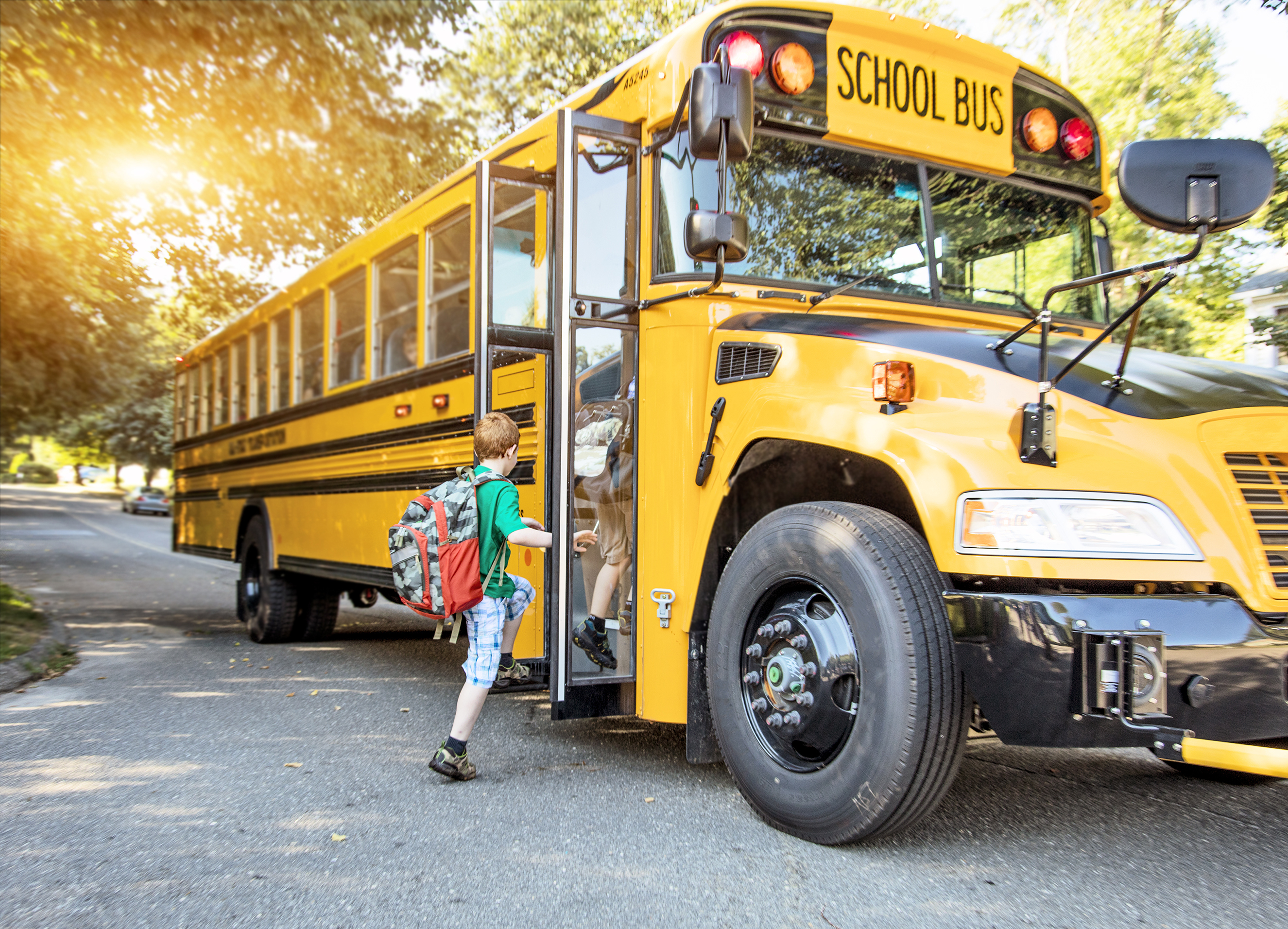 Image of a school bus on a street with children boarding it. 