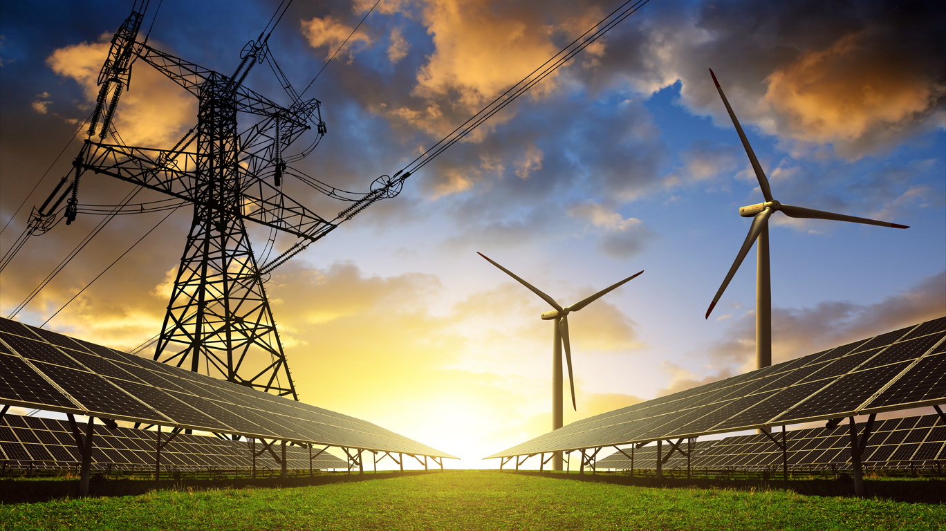 Image of wind turbines, solar panels, and electricity lines against a sunset