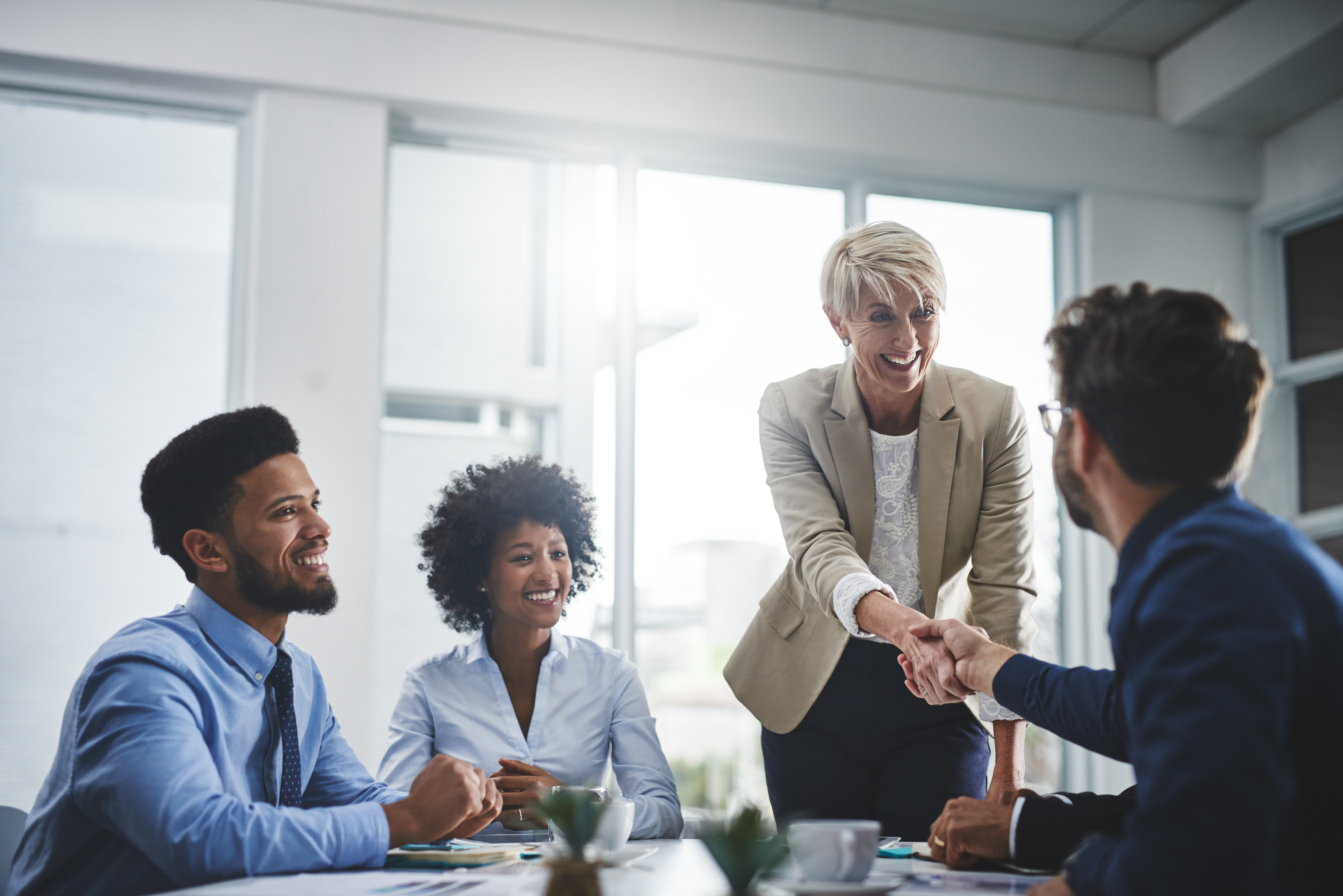 Four smiling professionals in business meeting