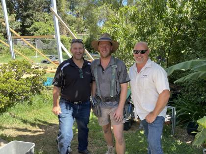 Three men standing in a grassy area in Australia