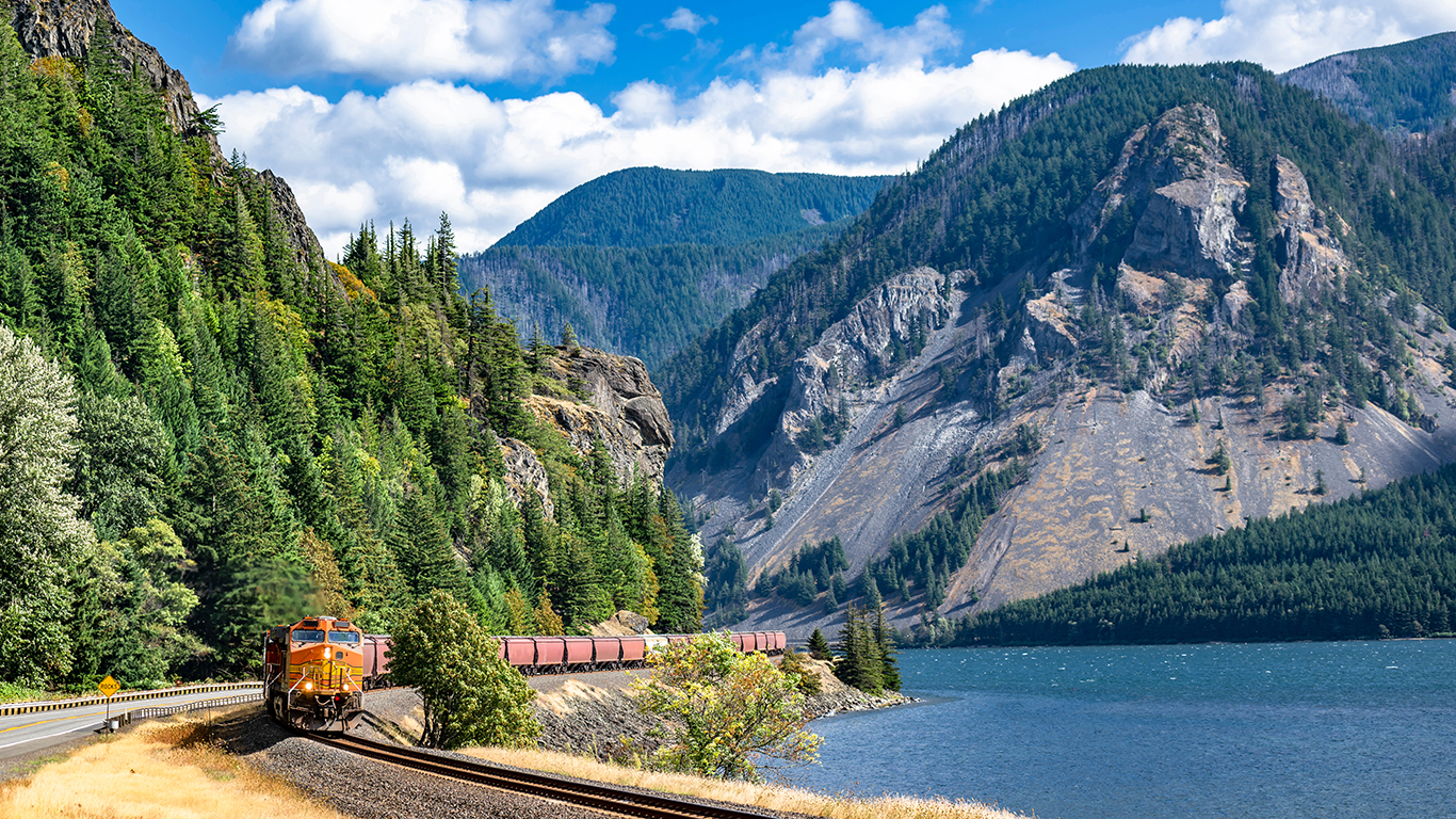 A freight train travels along the river through the mountains