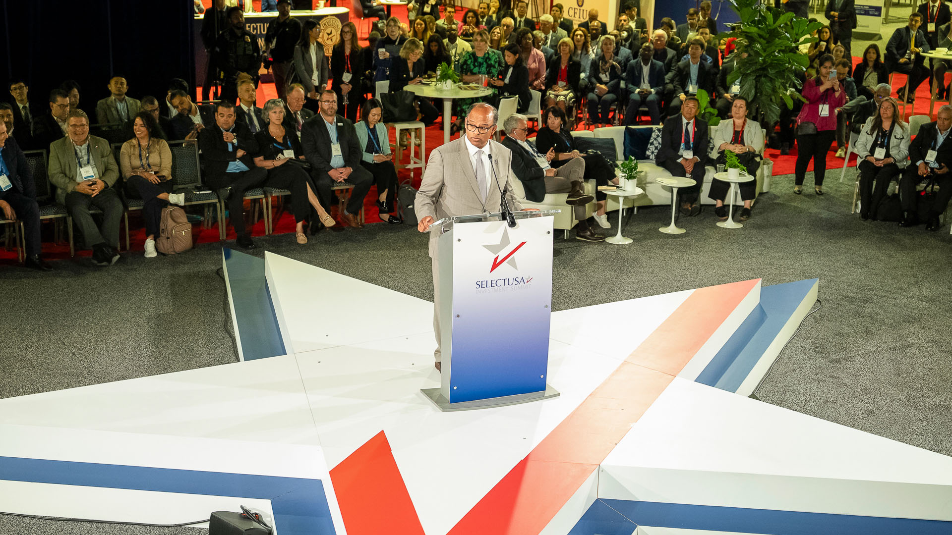 SelectUSA Executive Director Ashok Pinto speaks to a crowd from atop a star-shaped stage at the SelectUSA Investment Summit.