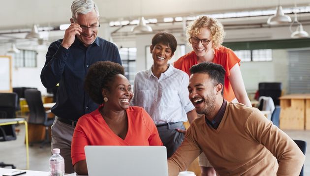 A photograph of a business team meeting around a laptop.