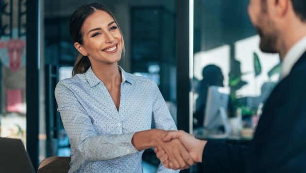 A photograph of a business team meeting up and shaking hands.