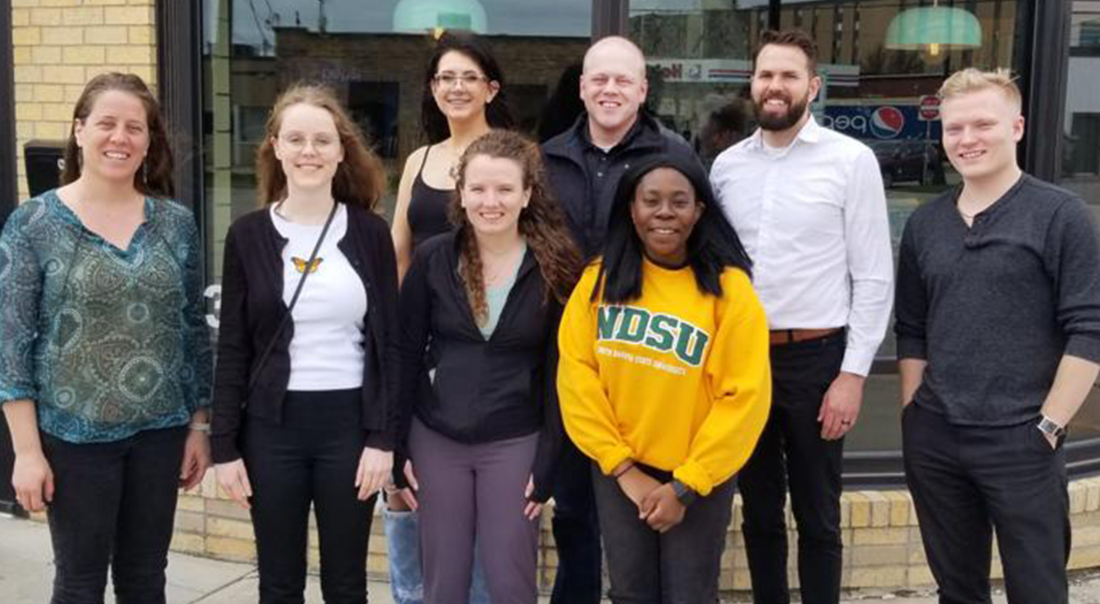 Group of eight people standing in front of a restaurant