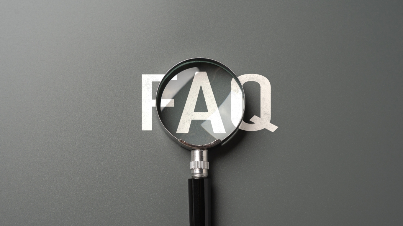magnifying glass over the words FAQ on a grey backdrop
