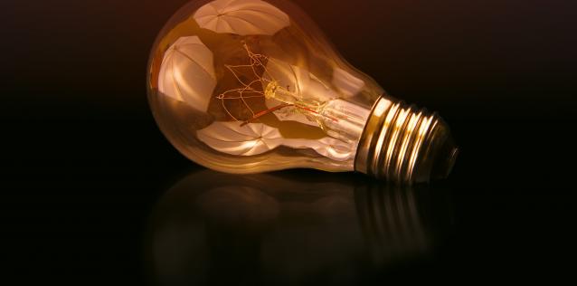 Illuminated lightbulb on side dark background