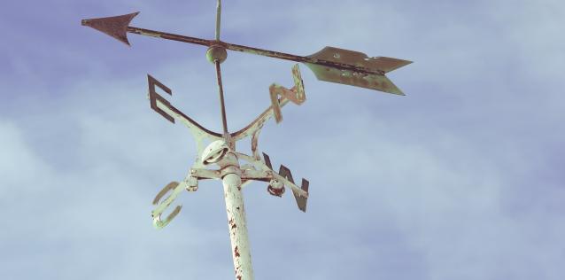 NSEW arrows with a blue cloudy sky