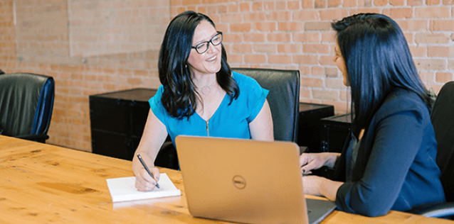 Two women having a professional discussion with at laptop computer in the foreground