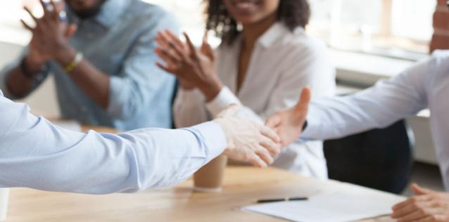 People shaking hands in a meeting. 