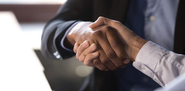 Two people shaking hands, focused in on hands. 