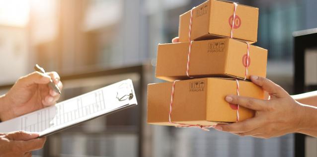 Delivery Man Holding Parcel Boxes While a Man is Signing Documents Image