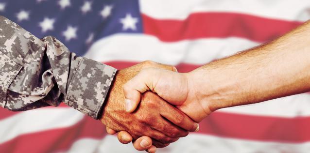 Military veteran shaking hands with business man in front of American flg