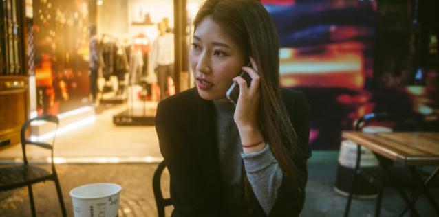 A woman sitting at a cafe, talking on the phone