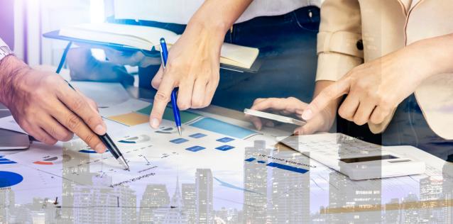 Image of people pointing to graphs and charts in a business meeting.