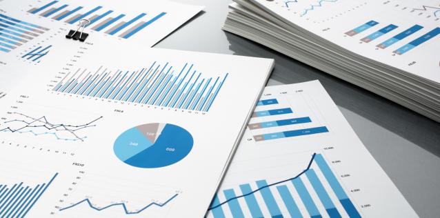 Blue graphs and charts. Business reports and pile of documents on gray reflection background.