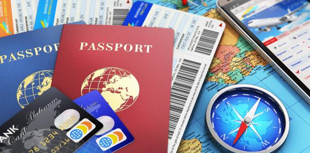 Travel picture with passports, airline tickets, cell phone with travel instructions and a map background and compass.