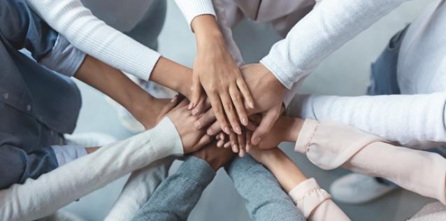 Multiracial business team putting hands on top of each other top view image.