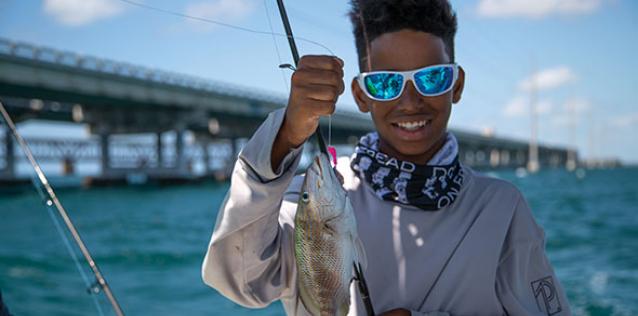 child showing fish and fishing pole